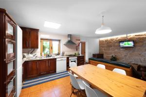 a kitchen with a wooden table and a dining room at Quinta da Tia in Baiões