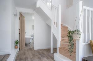 a white staircase in a home with white walls and wood floors at Brook Cottage - 7 Bedroom Cottage - Dale in Dale