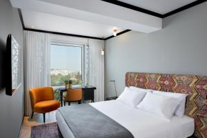 a bedroom with a bed and a desk and a window at Bat Sheva Jerusalem by Jacob Hotels in Jerusalem