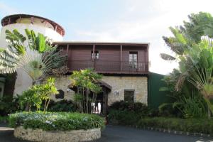 a house with a balcony and some palm trees at Auberge de la Vieille Tour in Le Gosier
