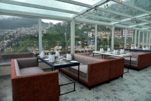 a restaurant with couches and tables and windows at The Orchid Hotel Shimla in Shimla