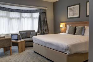 a hotel room with a large bed and a couch at Linton Lodge a BW Signature Collection Hotel in Oxford