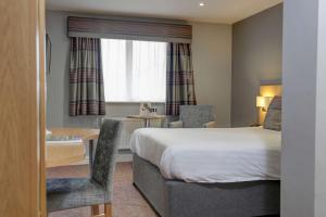 a hotel room with a bed and a table and chair at Linton Lodge a BW Signature Collection Hotel in Oxford