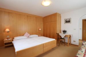 1 dormitorio con 1 cama grande y escritorio en Villa Resi B&B en Corvara in Badia