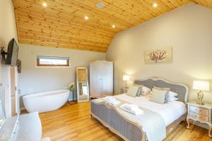 um quarto com uma cama grande e uma banheira em Thistle Lodge 18 with Hot Tub em Belladrum
