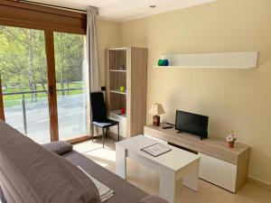 ein Wohnzimmer mit einem Sofa und einem TV in der Unterkunft Apartamentos Llorts Ordino 3000 in Llorts