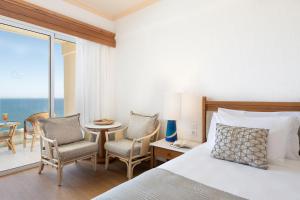 
a hotel room with a bed, table and chairs at Leptos Panorama Hotel in Kalamaki Chanion
