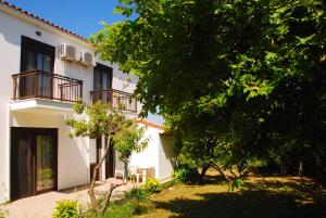 Casa blanca con 2 balcones y un árbol en Saonisos, en Kamariotissa