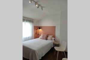 a bedroom with a white bed and a chair at Avenida 37 in Caldas de Reis
