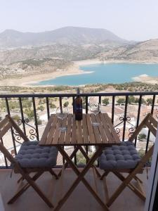 einen Holztisch und Stühle auf einem Balkon mit Blick auf den Strand in der Unterkunft Casa Rural Plaza Zahara Buenas Vistas in Zahara de la Sierra