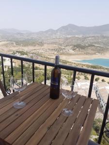 una botella de vino en una mesa de madera con copas de vino en Casa Rural Plaza Zahara Buenas Vistas, en Zahara de la Sierra