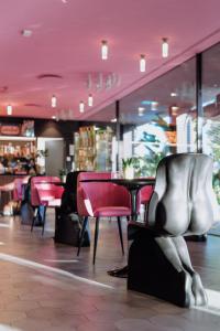 un restaurante con techos rosados, sillas y mesas en Collini Rooms, en Milán