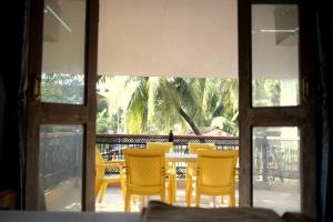 a dining room table with yellow chairs outside a window at Anna's Bungalow 4BHK in Alibaug