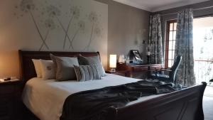 1 dormitorio con cama, escritorio y ventana en 2 Leafed Doors en Johannesburgo