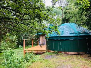 a tent with a wooden deck next to a river at Cotswolds Camping at Holycombe in Shipston-on-Stour