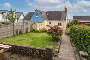 a yard with a bench and a house at Ivydene - Beautiful Cottage, Stone Throw from Beach, Wonderful Sea Views in Saundersfoot