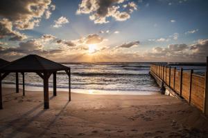 a sunset on a beach with a wooden pier at Dizengoff Avenue Boutique Hotel in Tel Aviv