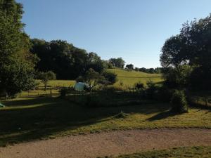 a field with a fence and trees in the background at Maison à la campagne in Lyaud