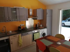 a kitchen with a table and a sink and a dishwasher at Maison à la campagne in Lyaud