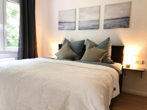 een slaapkamer met een wit bed met vier foto's aan de muur bij Apartment am Kurpark in Wilhelmshaven