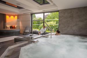 a woman sitting in a hot tub in a hotel room at Rivage Hôtel & Spa Annecy in Annecy