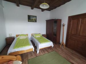 een slaapkamer met 2 bedden en een houten vloer bij Heni Vendégháza in Vadna