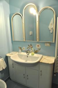 La salle de bains est pourvue d'un lavabo blanc et de deux miroirs. dans l'établissement Bed & Breakfast La dodicesima Notte, à Viggiano