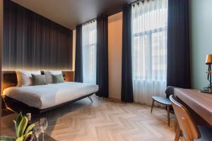 a bedroom with a bed and a desk and windows at Vinotel X in Tongeren