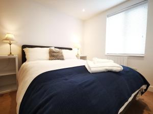 a bedroom with a large bed with a blue blanket at Apartment in the heart of East Wittering Village in Chichester