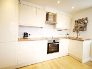 a white kitchen with white cabinets and a sink at Apartment in the heart of East Wittering Village in Chichester