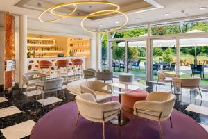 un ristorante con tavoli, sedie e un lampadario di Hotel Vatel 4* Superior a Martigny-Ville