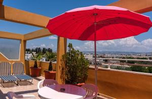 a red umbrella on a balcony with a table and chairs at Apollonia Hotel Apartments in Paphos City