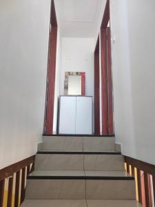 Elle comprend un couloir avec des escaliers et un réfrigérateur blanc. dans l'établissement Petite maison à 12mn du bassin de Manapany, à Saint-Joseph