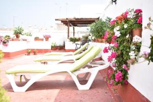 eine Reihe von Liegestühlen auf einer Terrasse mit Blumen in der Unterkunft Apartamento La Discusión de Veedor 12 in Cádiz