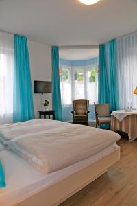 a bedroom with a large bed with blue curtains at Hotel Markgräfler Hof in Badenweiler