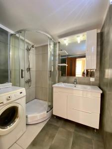 een badkamer met een douche, een wastafel en een wasmachine bij Central Apartments in Odessa