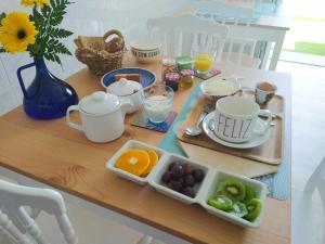 una mesa con tazas y una bandeja de fruta. en Farol Guesthouse, en Angra do Heroísmo