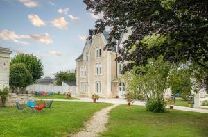 a house with chairs in the grass in front of it at Manoir des Bertinières in Cravant-les-Coteaux