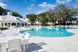 a swimming pool with white tables and chairs next to a building at The Equestrian in Ocala
