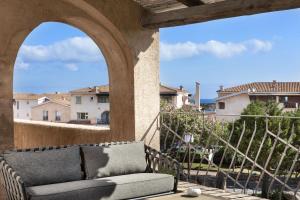 ein Sofa auf einem Balkon mit Blick auf die Gebäude in der Unterkunft Le Suites Porto Cervo in Porto Cervo