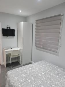 a bedroom with a bed and a desk and a window at Cosy Lodge in Thornton Heath