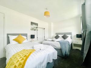 a bedroom with two beds with white and yellow pillows at Central Hamilton House in Hamilton