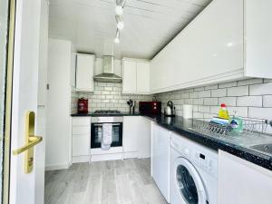 een keuken met witte kasten en een wasmachine en droger bij Central Hamilton House in Hamilton