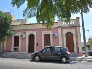 a small car parked in front of a pink building at Pink liberty house in Santa Croce Camerina