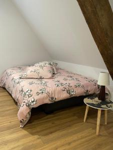 1 dormitorio con cama con edredón rosa y mesa en Gîte Les lavandières, en Colmar