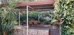 un patio con mesa y sillas bajo una pérgola en Mountain Gem en Bloemfontein
