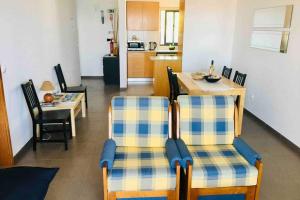 ein Wohnzimmer mit zwei Stühlen und einem Tisch in der Unterkunft Apartamento Vista do Mar B in Ribeira Quente