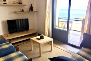ein Wohnzimmer mit Fernseher, Couch und Tisch in der Unterkunft Apartamento Vista do Mar B in Ribeira Quente