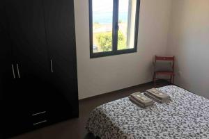 ein Schlafzimmer mit einem Bett, einem Fenster und einem Stuhl in der Unterkunft Apartamento Vista do Mar B in Ribeira Quente