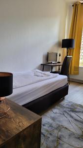 een slaapkamer met een bed en een bureau met een laptop bij Hotel Kronprinz in Emden